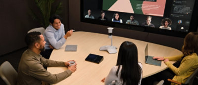 A group of people sitting on a table with their laptop engaged in a discussion