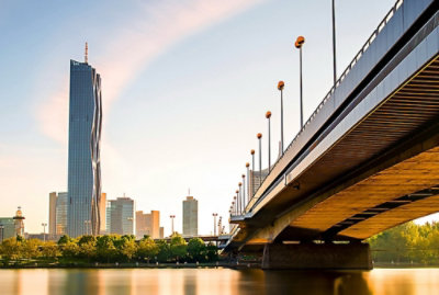 街の建物を背景にした、水に架かる照明付きの橋。