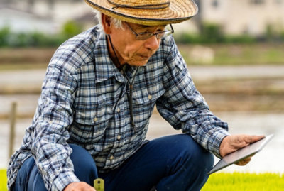 麦わら帽子をかぶり、眼鏡をかけた男性が一枚の紙を見ています。