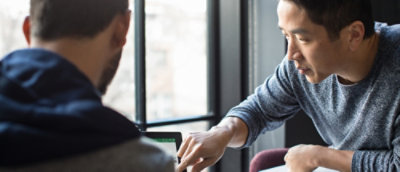 A man sitting in front of a window with a laptop.