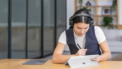 A woman wearing headphone and using tab