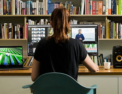 A woman working at a desk with two monitors and a laptop.