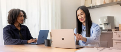 A man and woman sitting at a table with laptops.