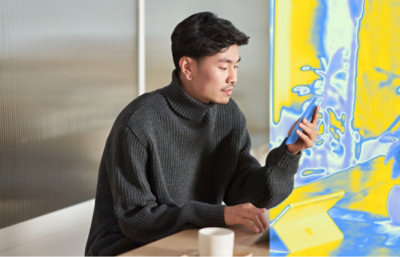 A person holding a phone while wearing a grey sweater.