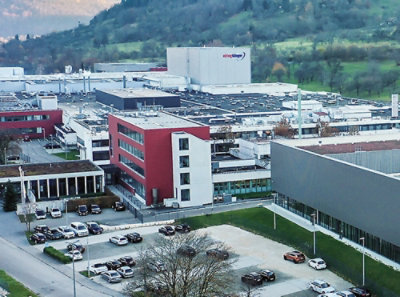 A large building with a parking lot and trees nearby.