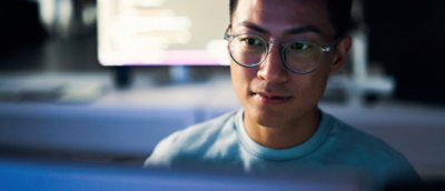 A man wearing glasses is looking at a computer screen.