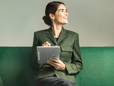 A woman in a green blazer holding a tablet. 