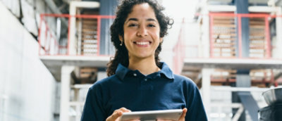 A girl in a dark blue shirt smiling and holding a tab.