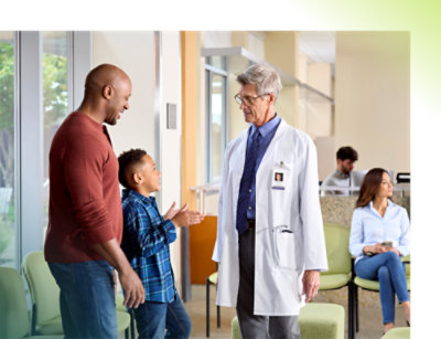 A doctor wearing a white lab coat talking to a child.