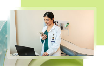 A woman in a white coat holding a phone.