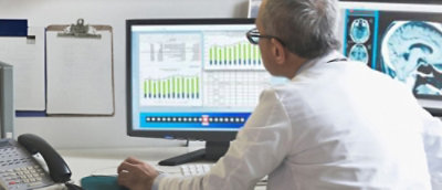 A man in a white coat looking at a computer screen.
