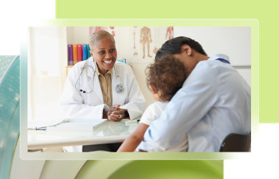 A doctor and a child sitting at a table in a medical office.