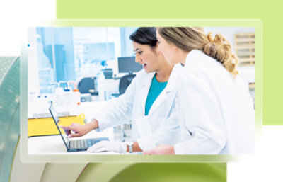 People wearing lab coats gathered around a laptop.