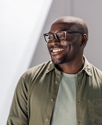 A man wearing glasses looking off to the right and smiling.