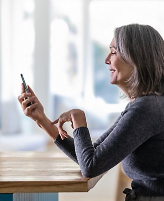  A women sitting at a table looking at a cell phone.