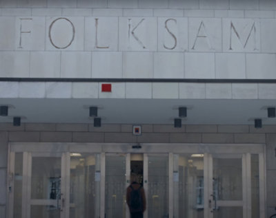 En kvinde, der sidder ved et bord med mænd og bærbare computere.