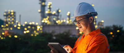 en person iført industrihjelm og arbejdstøj, der kigger på en tablet