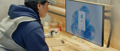 A woman in a blue jacket looking at a computer screen displaying a blue image.