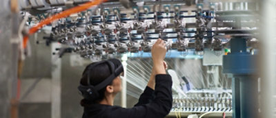 Osoba s náhlavní soupravou pro virtuální realitu a sluchátky při interakci se zařízením.