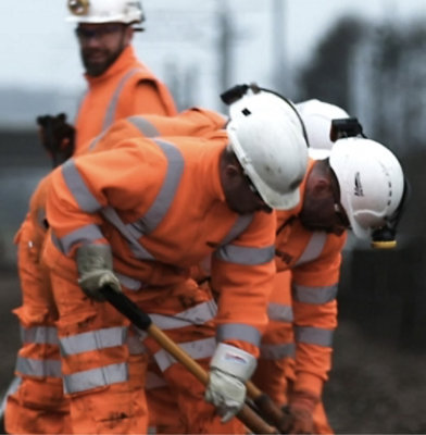 Skupina stavebních dělníků v oranžových uniformách