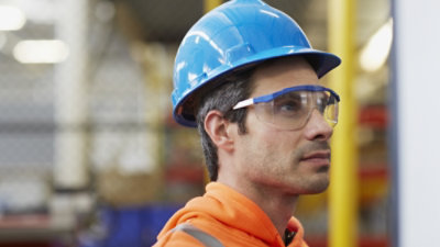 Detailní záběr muže v ochranné helmě a brýlích.