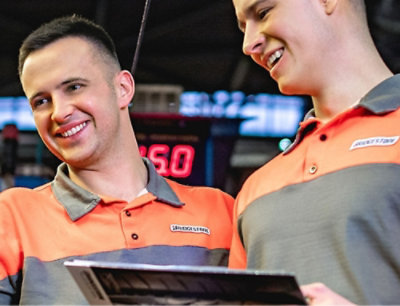 A man smiling at a tablet with another man beside him.