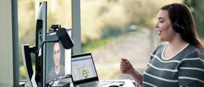 A woman wearing headphones sitting at a desk with a laptop and a microphone nearby.