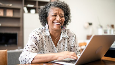 A person with curly hair wearing a headset and smiling.