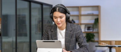 Una mujer con auriculares mirando una tableta.