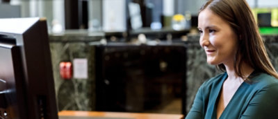 Una mujer sonriendo y mirando un portátil.