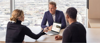 Un grupo de personas sentadas en una mesa con un portátil.