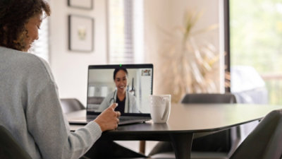 A woman talking to a doctor on a laptop.
