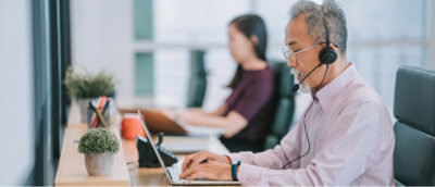A man wearing a headset using a laptop.
