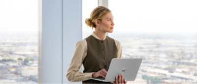 A woman in a vest holding a laptop.