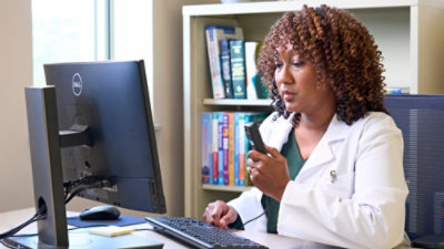 En kvinne i en hvit frakk som holder en telefon.