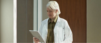 En kvinne i hvit frakk som holder et nettbrett.