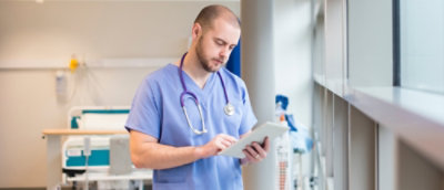 Un doctor îmbrăcat în halat medical și cu stetoscop utilizează o tabletă.