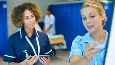 O asistentă într-un spital ținând o tabletă.