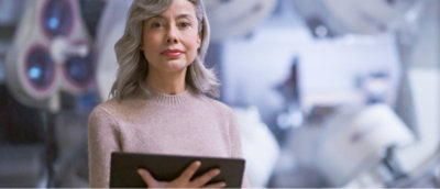 O femeie cu păr cărunt ține o tabletă.