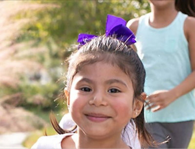 一个头发上戴着紫色蝴蝶结的女孩。