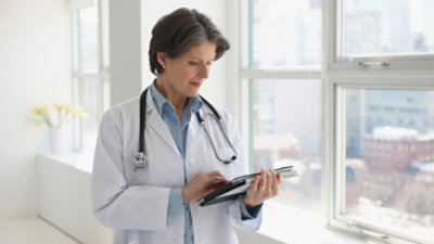 一名医生拿着平板电脑设备使用。