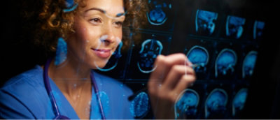 身穿蓝色刷手服看大脑图像的女子特写。