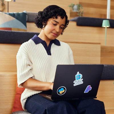 ベンチに座ってノート PC を使用している人。