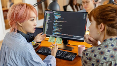 コンピューターの画面を見ているデスクに座っている人々のグループ