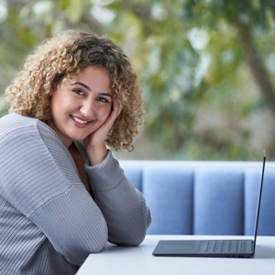 A girl with smiling face infront of laptop