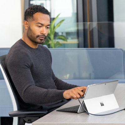 En person sitter vid ett bord med en surfplatta.