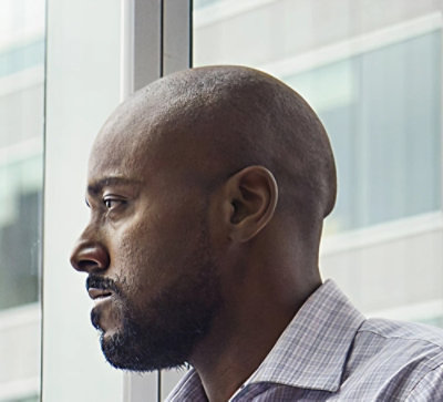 En man tittar ut genom ett fönster.