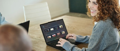 Woman with curly hair smilling while working on the laptop and looking away