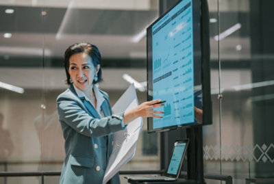 A woman explaining while pointing at the screen with some data