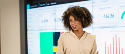 A woman with curly hair explaining while some data been displayed in the background